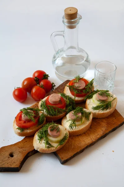 Masada domatesli sandviçler. Yanlarında iki bardak domates ve bir şişe var. Beyaz bir arkaplanda.