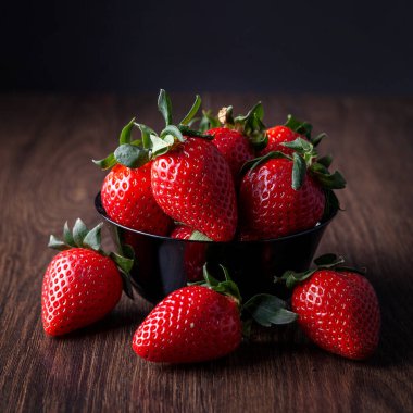 Tabakta çilek var. Karanlık bir arka planda. 