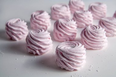 Masanın üzerinde pembe bir şekerleme var. Beyaz bir arka planda. Seçici odak.