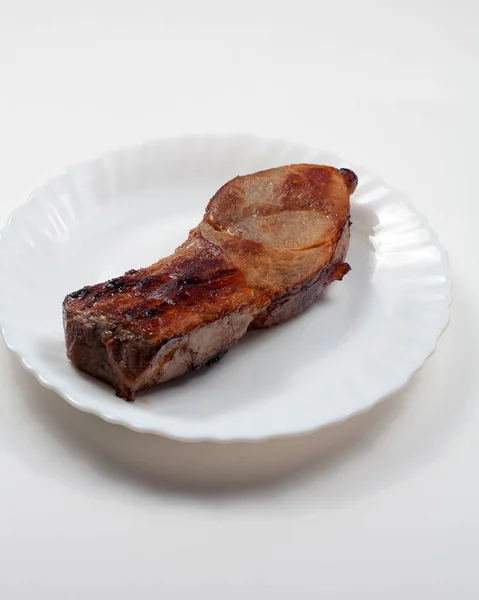 Masanın üzerinde bir tabak dolusu kızarmış et var. Beyaz bir arkaplanda.