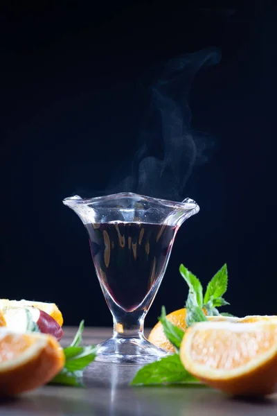 Masada bir bardak sıcak şarap var. Bir bardak buhar yüzünden. Limon, nane ve elmanın yanında. Seçici odak.