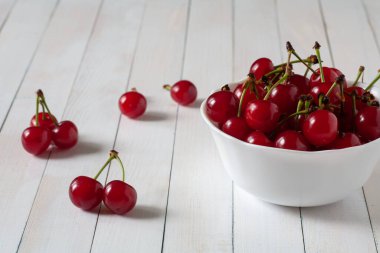Masada beyaz bir tabakta kirazlar var. Beyaz bir arka planda. Seçici odak.