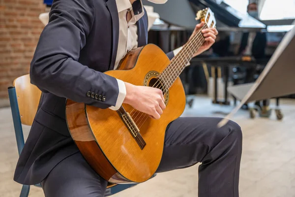 Hombres tocando la guitarra Guapos jóvenes sentados en la silla y tocando la guitarra acústica — Foto de Stock