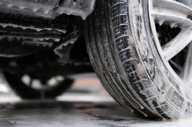 Manual car wash with white soap, foam on the body. Washing with soap.