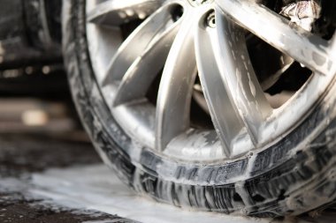 High Pressure Water. Close up. Manual car wash outside. Manual car wash with white soap, foam on the body.