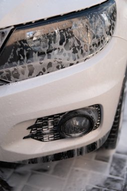 car wash with white soap, foam on the body. Cleaning Car Using Washing with soap. High Pressure Water.
