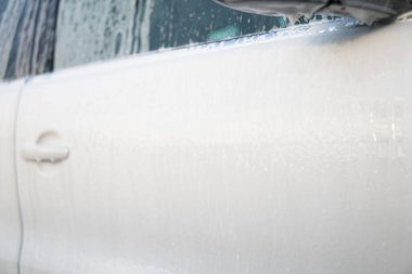 Cleaning Car Using Washing with soap. Manual car wash with white soap, foam on the body. Close up. Manual car wash outside. High Pressure Water.