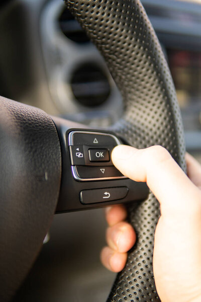 A hand hold Black leather Steering wheel of a car to drive with blurred car dashboard as background ,selective focus ,car driving concept