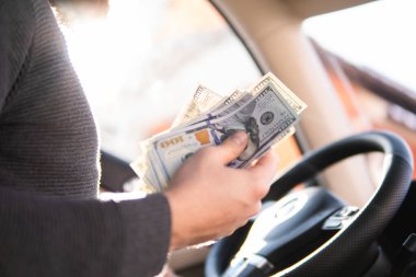 Arabadaki direksiyonun arka planında bir dolarlık banknotlar var. Kazanç veya rüşvet kavramı, sigorta veya kredi, yatırım veya araba satmak