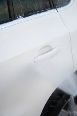 Sabunla yıkıyorum. Elle oto yıkama dışarıda. Elle yıkama ve beyaz sabun. Kapatın. Yüksek Basınçlı Su. Vücutta köpük var. Dikey çekim kullanarak Araba Temizleme