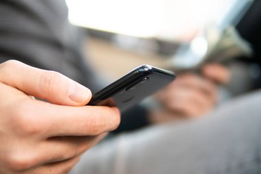 Gençler araba kullanır ve akıllı telefon kullanır. Araba kullanırken cep telefonu tutan genç bir adam mesajları okuyor. Tehlikeli davranış, kaza riski. Tehlike