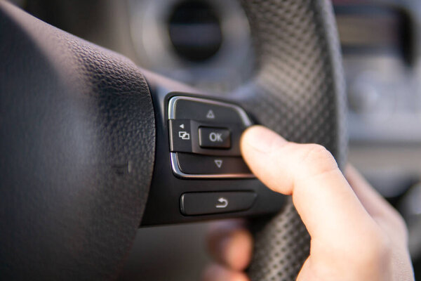 Man's hands of a driver on steering wheel of a minivan car on asphalt road