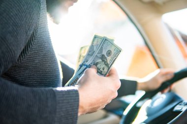 Arabadaki direksiyonun arka planında bir dolarlık banknotlar var. Kazanç veya rüşvet kavramı, sigorta veya kredi, yatırım veya araba satmak