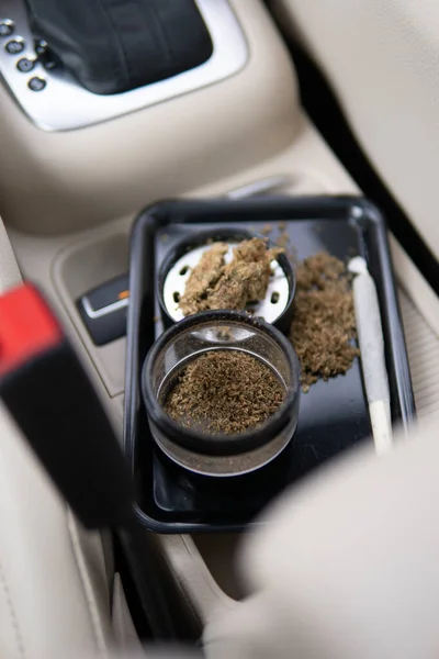 研磨机和切碎的大麻关节和汽车底座上的一包杂草关闭了大麻花蕾 — 图库照片