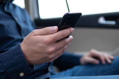 Şatonun arka planında cep telefonu kullanan bir adam. Bulanık Hipster mesajında erkek elleri aygıtı tutuyor