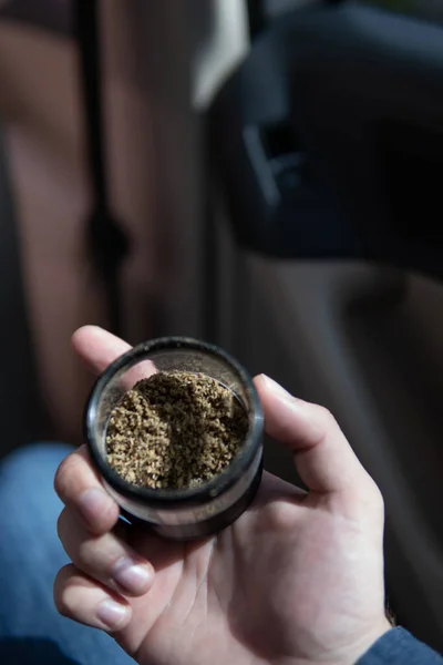 Flores de cannabis. amoladora en mano maleza en un coche fondo cerca de brote de marihuana —  Fotos de Stock