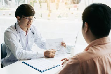 Doktor hasta geçmişi listesini not defterine yazmış ve hastayla ilaç ve tedavi hakkında konuşmuş..