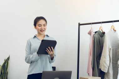 Genç Asyalı girişimciler online satın alma siparişlerini kontrol ederken bir tablet kullanıyorlar.