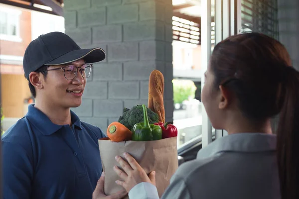 stock image Delivery of an asian man handling a bag of food to a female customer at the door.
