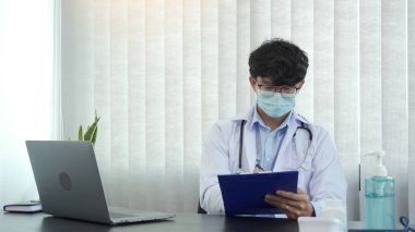 Doktor, elinde kalem tutarak hasta geçmişi listesini panoya yazıyor. İlaç ve tedavi hakkında..