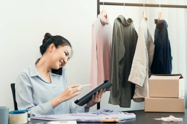 Bir tabletin envanterini kontrol ederken Asyalı girişimci bir müşteriyle telefonda konuşuyor..