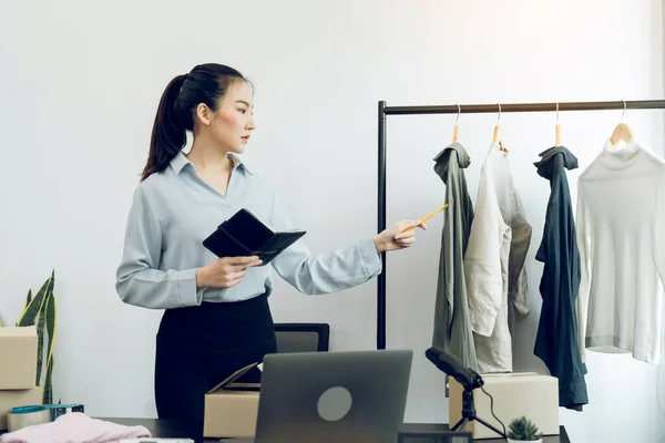 若いアジアの起業家は 顧客に販売する前に服をチェック — ストック写真