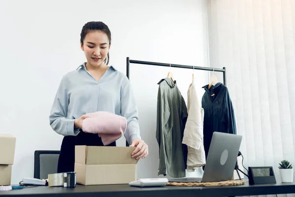 アジアの起業家は 顧客への配達のために紙箱で販売することができる彼女の服を準備しています — ストック写真