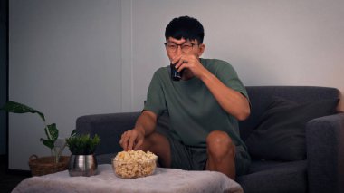 Asyalı adam hafta sonu için evinde dizi izleyerek rahatlıyor..