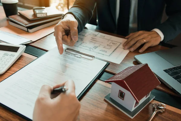Sigorta komisyoncuları sigorta kontratının imzalandığına işaret ediyor ve ofisteki müşterilere açıklıyorlar..