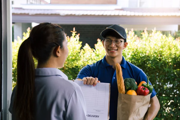 Supermarket food delivery staff deliver bags to female customers in front of the house.