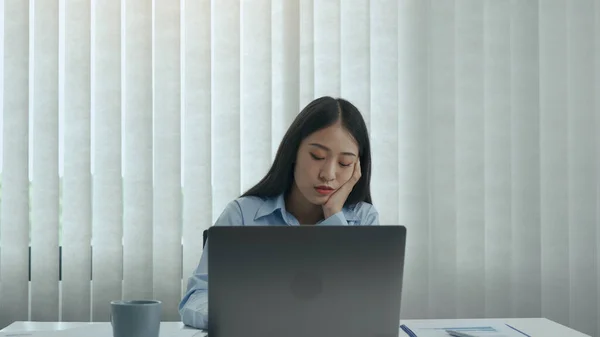 Young asian women are bored at work and feel lazy to deal with data on their laptop in the afternoon.