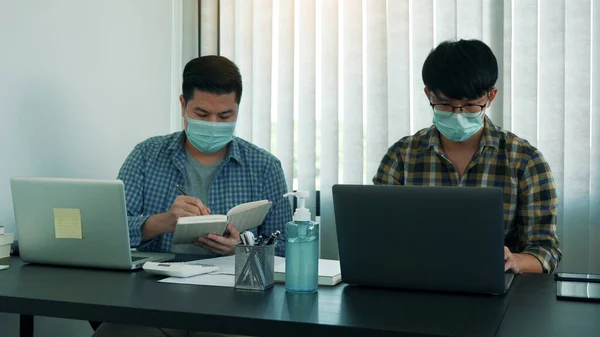 アジア人の同僚が事務所で働いてるウイルス発生時にマスクをしてる — ストック写真