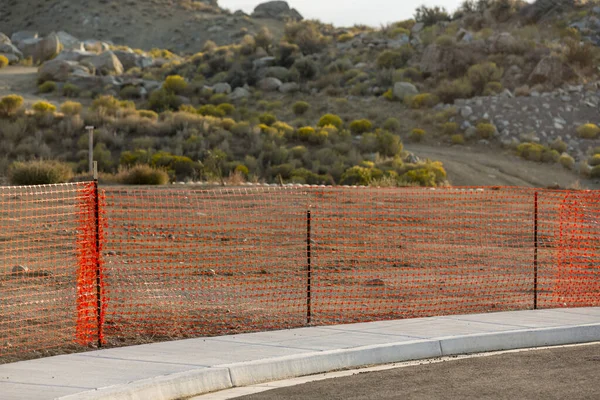 砂漠の丘の近くにオレンジ安全柵がたくさん並んでいます ストック画像