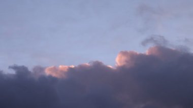 Pembe ve mavi bulutlar gün batımında gökyüzünde yavaşça ilerliyorlar.
