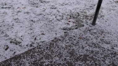 Karanlık bir günde verandaya ve çimlere mermer büyüklüğünde dolu düşer..
