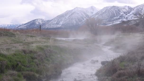 흐르는 샘물에서 불어오는 수증기 속에서 눈덮인 산들을 바라보면서 — 비디오