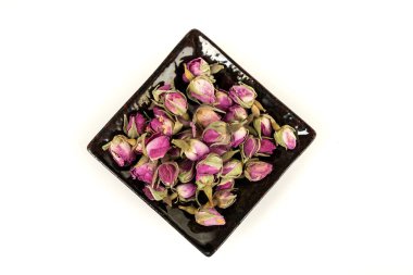 Seramik bir tabakta kurumuş pembe gül tomurcukları.