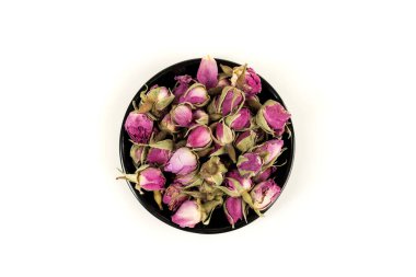 Siyah bir kasede kurumuş pembe gül tomurcukları.