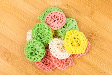 Çok renkli tapyoka krakerleri kesme tahtasının tepesinde, beyaz üzerine izole edilmiş.