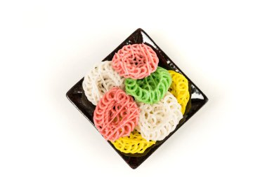 Seramik tabakta çok renkli tapyoka krakerleri var, beyaz üzerine izole edilmiş.