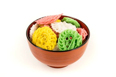 Turuncu bir kasedeki çiğ, renkli tapyoka krakerleri beyazın üzerinde izole edilmiş.