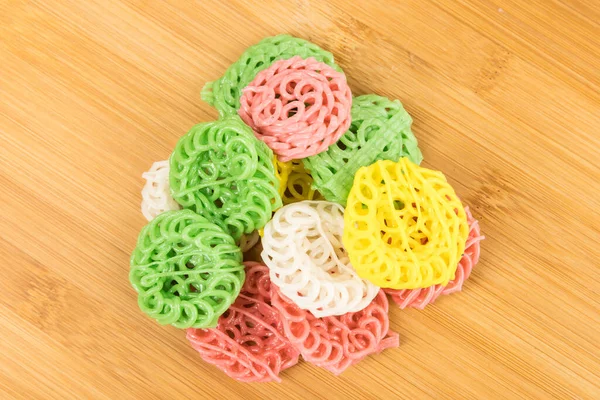 Çok renkli tapyoka krakerleri kesme tahtasının tepesinde, beyaz üzerine izole edilmiş.