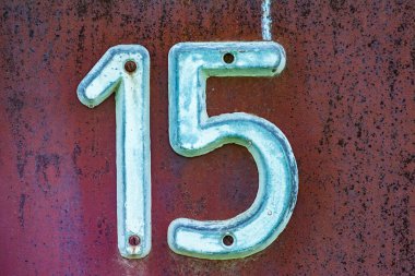 Evin eski plakası, üzerinde 15 yazıyor. Kırık kırmızı boya ve pas lekeleri. Eski evin adresi on beş numara..