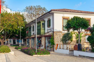 Alanya, Türkiye - 11.29.2022: Güneşli bir yaz gününde Türkiye tatil beldesinde güzel bir cadde. Güzel yeşil balkonları olan iyi korunmuş eski bir ev..