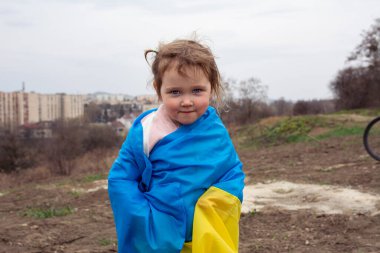 Ukrayna bayraklı güzel bir kız çocuğu Ukrayna 'nın bir şehrinde bir gölün ve şehrin arka planında. Ukrayna bayrağıyla vatansever bir kızın portresi..
