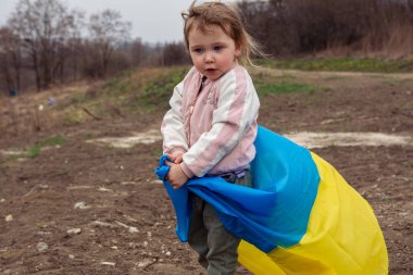 Ukrayna bayraklı güzel bir kız çocuğu Ukrayna 'nın bir şehrinde bir gölün ve şehrin arka planında. Ukrayna bayrağıyla vatansever bir kızın portresi..