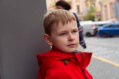 Ciddi çocuk. Kırmızı ceketli bir çocuğun ciddi yüzü. Beyaz bir çocuğun portresi..