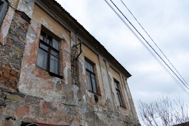 Bulutlu bir günde eski bir taş evin pencereleri. Ukrayna 'nın taşra şehri Chernivtsi' nin mimarisi. Alçı duvarları soymuş ve tuğlaları ortaya çıkarmış..