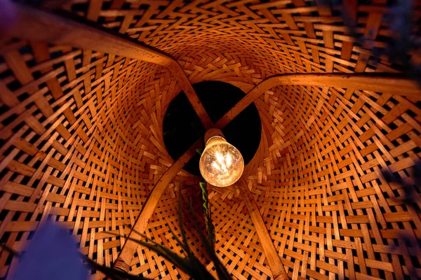 Hasır bir ahşap abajurlu bir lamba, güzel bir alt manzara. Sıcak ev atmosferi, sıcak ışık, çevre dostu malzemeler..