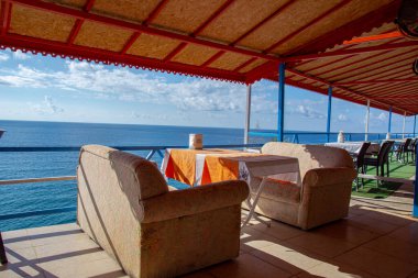 Deniz kenarındaki kafe. Güzel deniz manzarası, masalar ve sandalyeler. Güneşli bir yaz gününde deniz kıyısında terk edilmiş bir kafe..